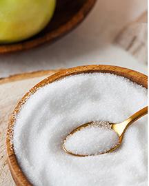 A spoon scooping sugar from a bowl 